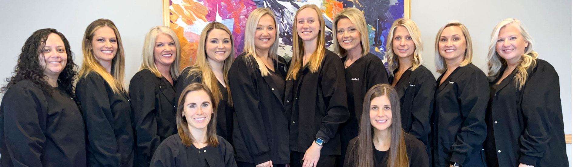 Dentists in Columbia, MO, with their dental team sharing smiles for a photo.